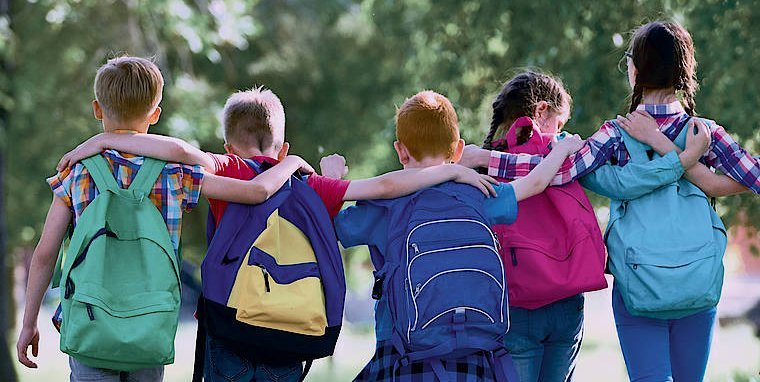 Schulkinder gehend, von hinten, einander umarmend
