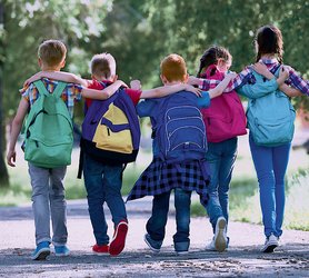 Schulkinder gehend, von hinten, einander umarmend