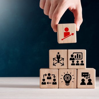 Hand, die eine Pyramide aus Würfeln aufbaut, die unterschiedliche Symbole abbilden