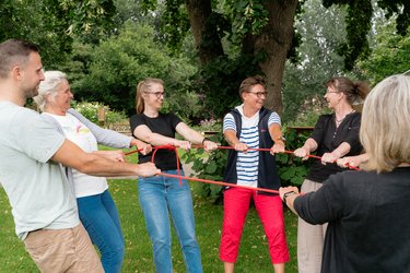 teilnehmende und Fachbreichleitung mit einem Seil in der Hand im Kreis stehend