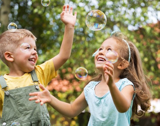 Zwei spielende Kinder mit Seifenblasen