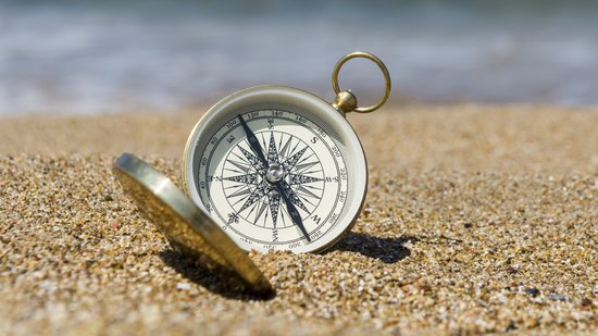 Ein Kompass liegt aufgeklappt am Strand