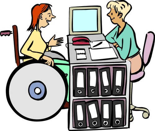 Frau im Rollstuhl sitzt vor einem Schreibtisch und wird von einer Frau beraten