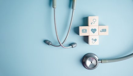 Abstraktes Stillleben aus Stethoskop und Würfelkreuz mit unterschiedlichen medizinischen Symbolen