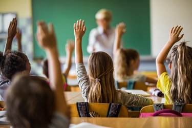 Sich meldende Kinder in einer Grundschulklasse von hinten aufgenommen