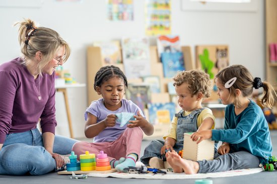 Erzieherin im Spiel mit drei Kleinkindern