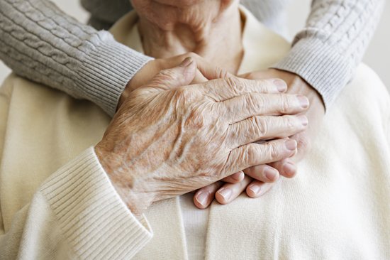 Hand einer alten Frau, die auf den Händen einer jungen Frau liegt
