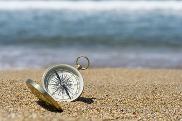 Ein Kompass liegt aufgeklappt am Strand