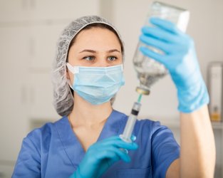 Junge Pflegefachkraft, die eine Spritze aufzieht