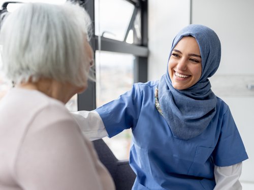 Muslimische weibliche Pflegefachkraft im Gespräch mit einer Seniorin